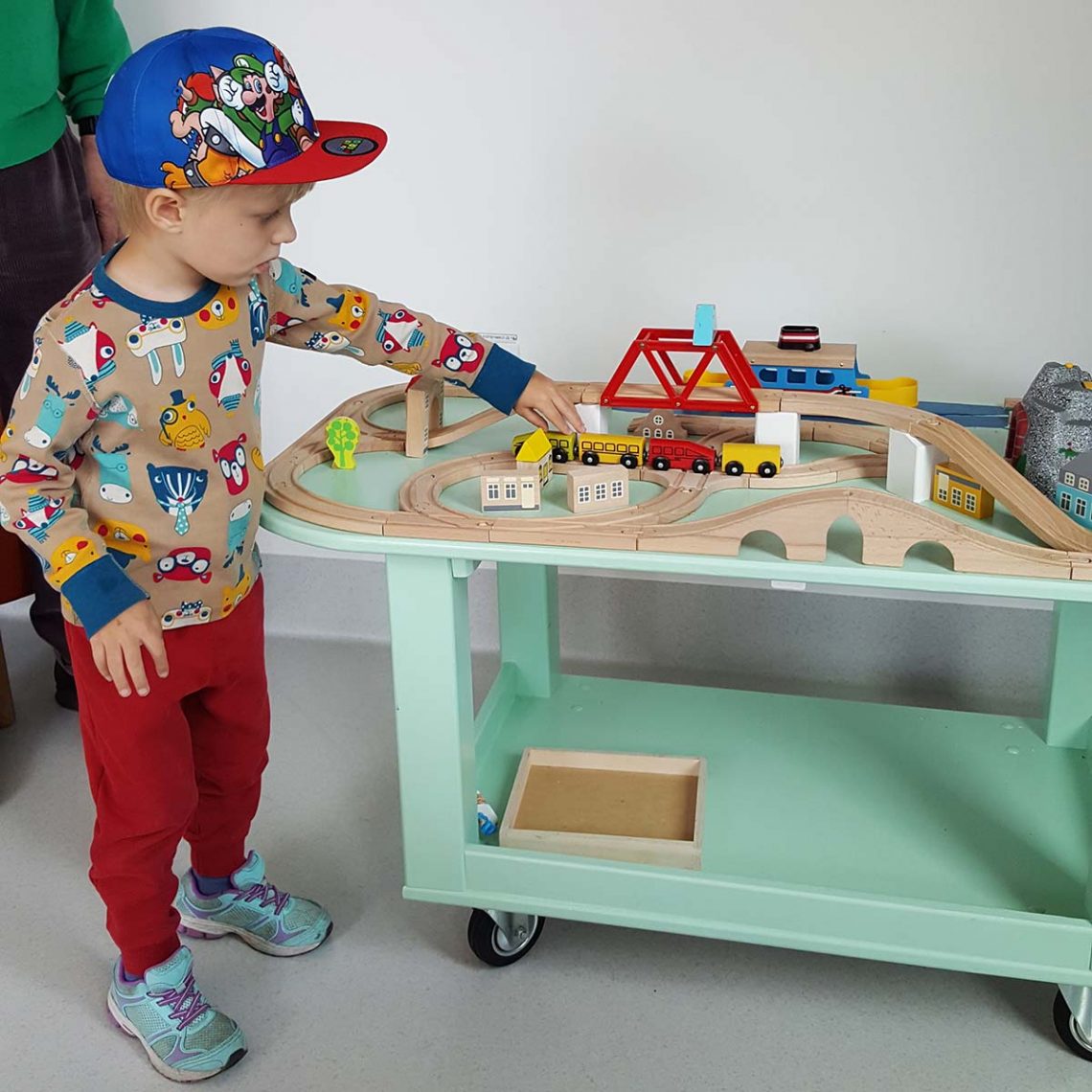 Elis leker med ett Brio-tåg medan mamma och pappa pratar med läkaren.