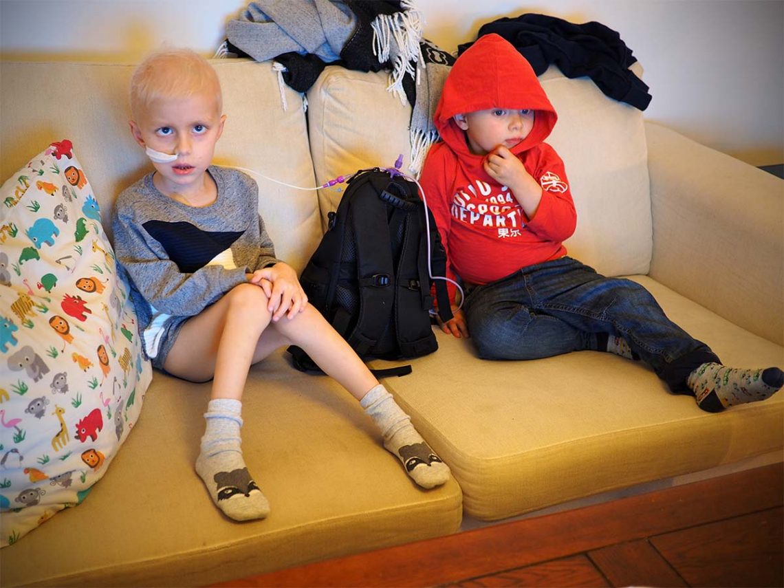 Elis och Folke i soffan framför tv:n, med sondpumpen mellan sig.