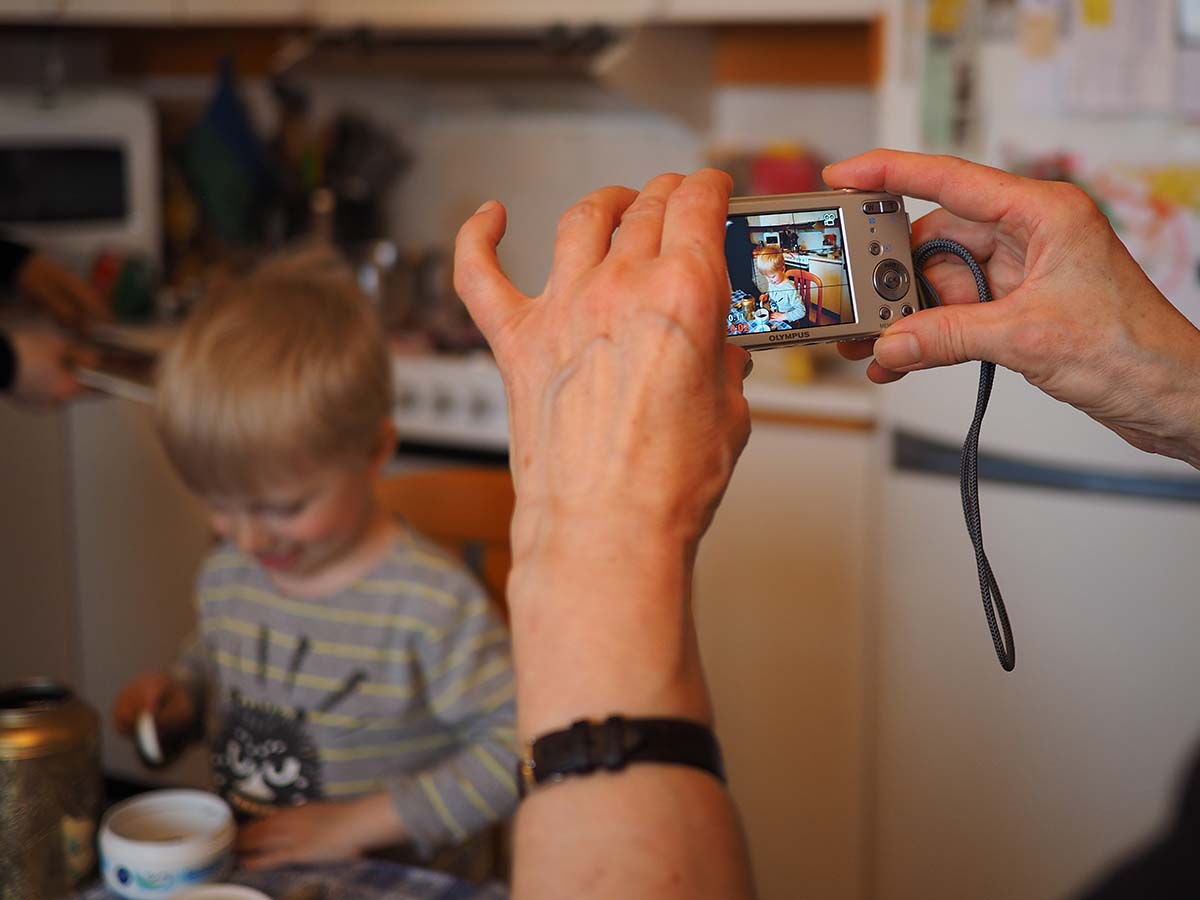 Farmor fotograferar Elis när han leker med tebladen.