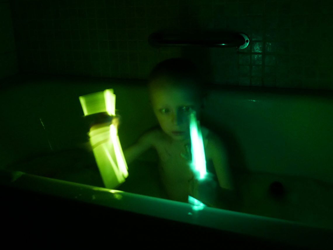 Elis i badet med två glowsticks