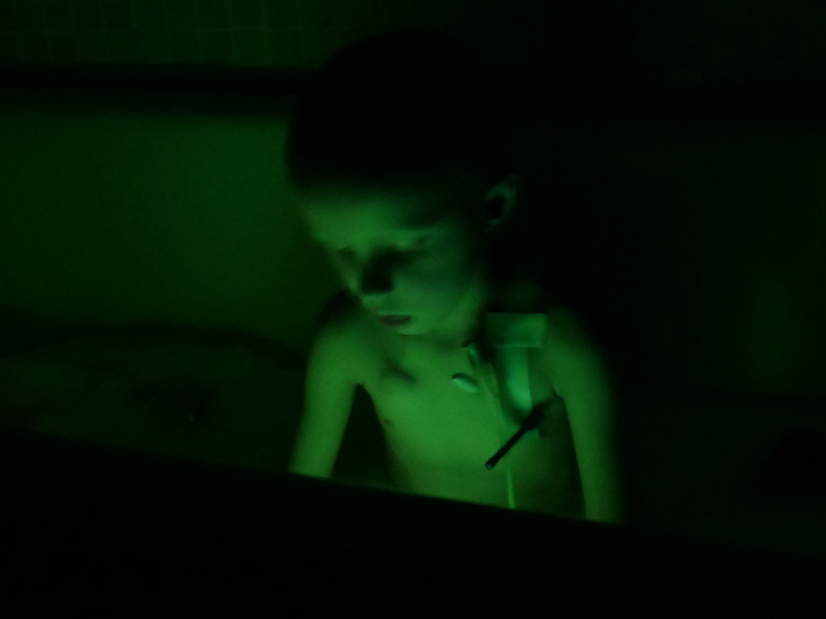 Elis i badet, med två glowsticks i vattnet