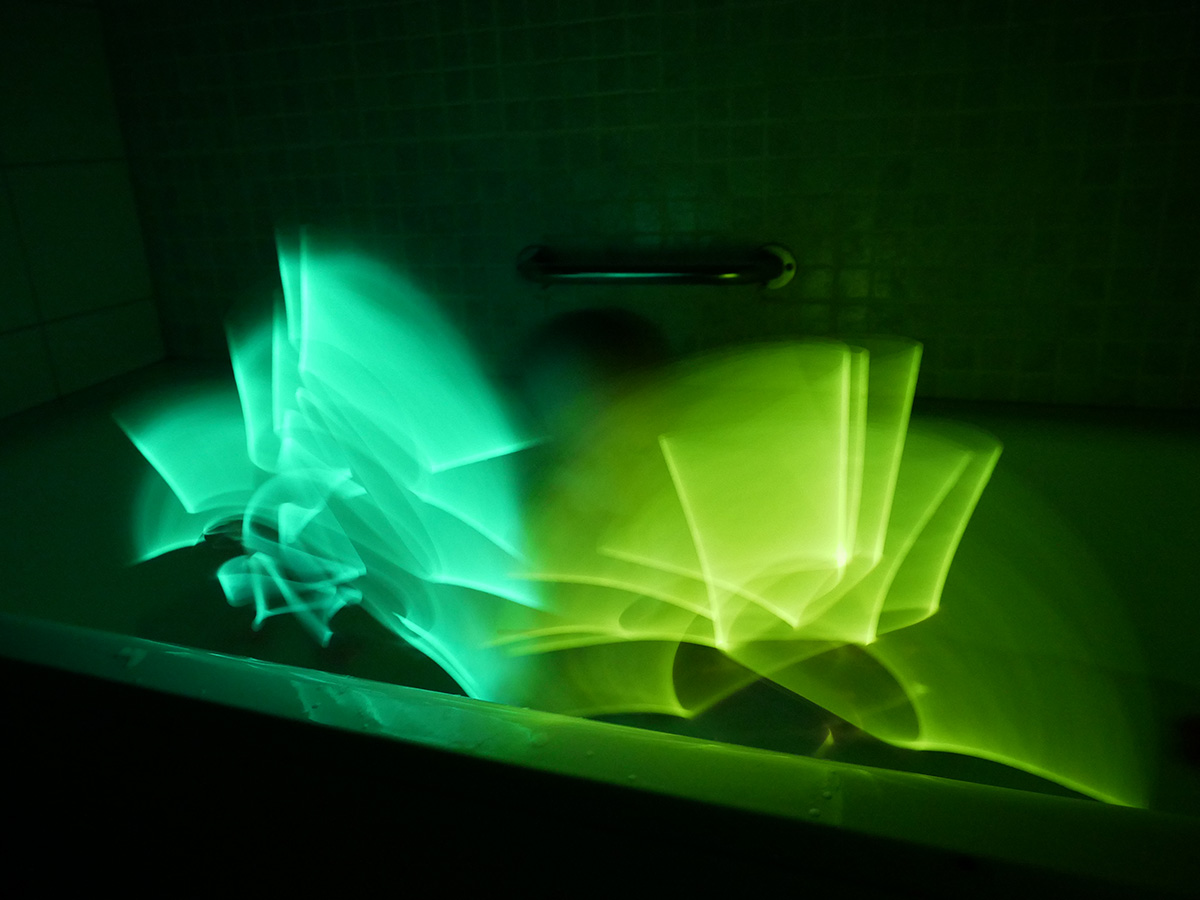 Elis viftar med två glowsticks medan han badar