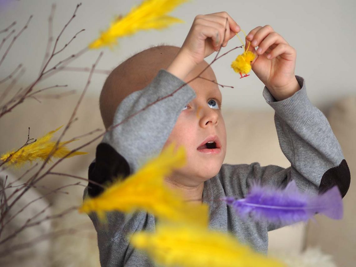 Elis pyntar påskriset med en liten kyckling