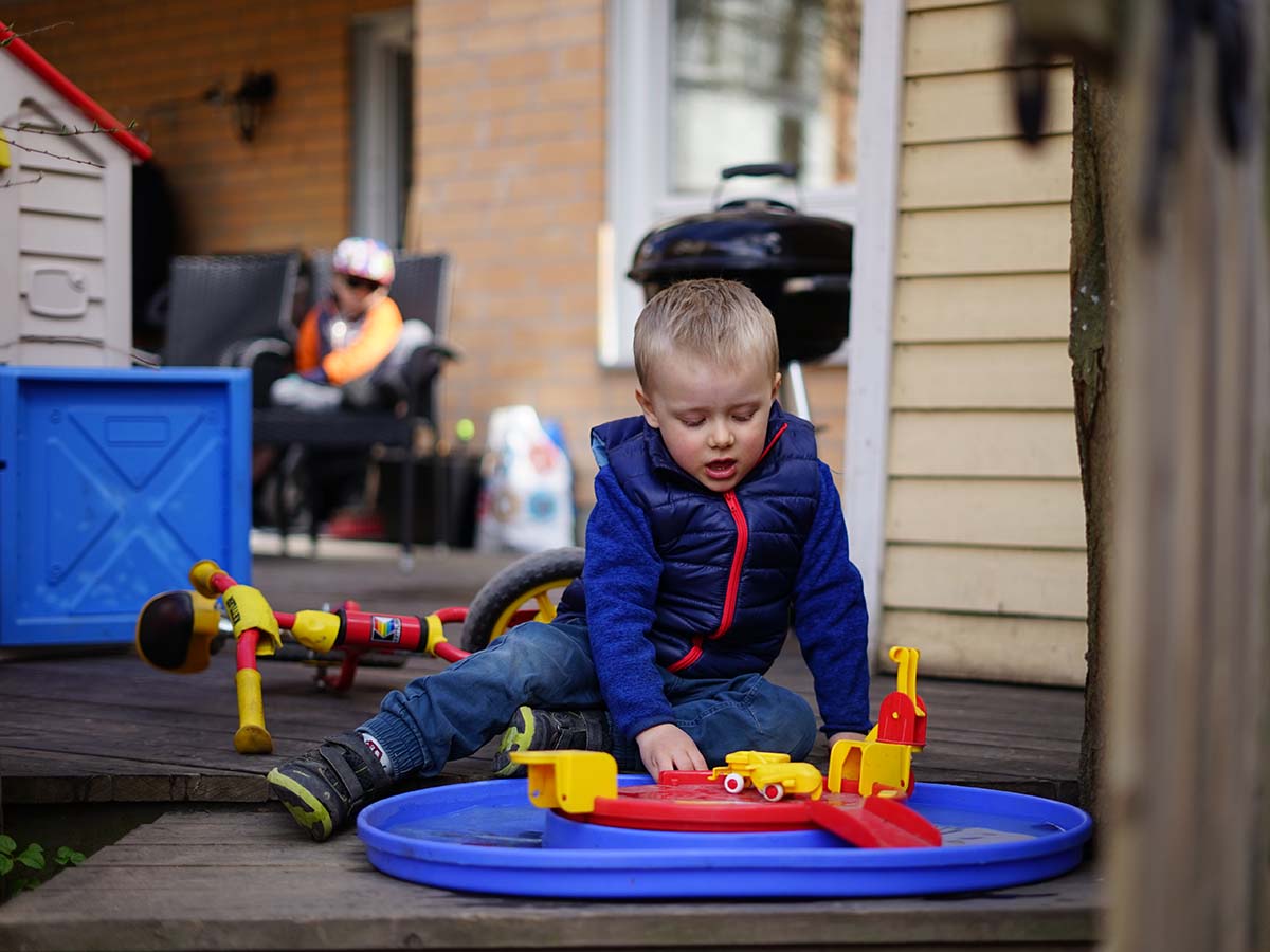 Folke leker på uteplatsen med Elis i bakgrunden