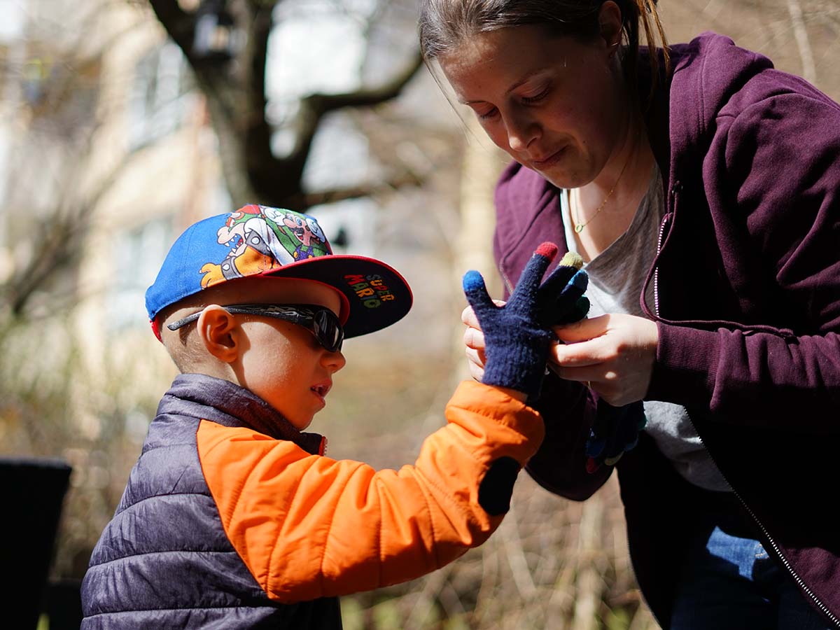 Mamma hjälper Elis med vanten på uteplatsen