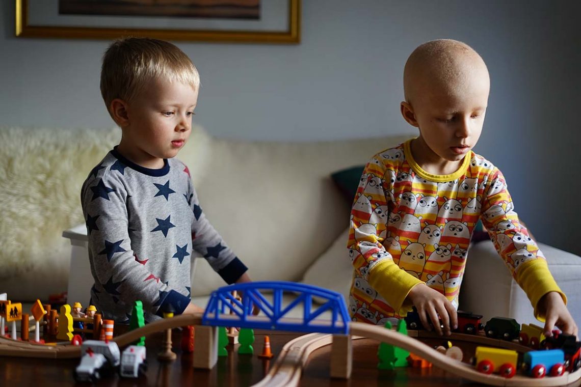 Folke och Elis leker med en träjärnväg hemma på soffbordet.