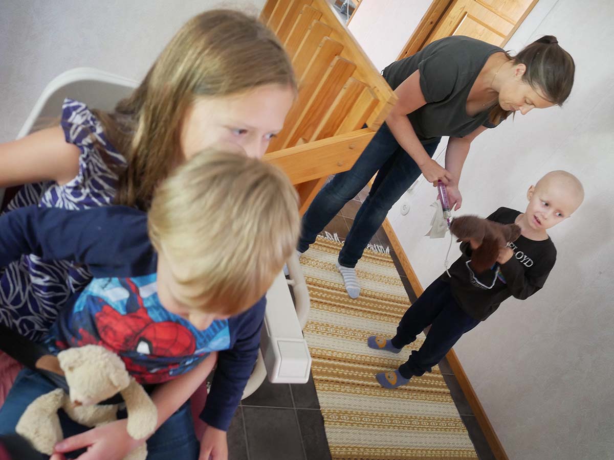 Folke och Lilly sitter i trapphissen, medan mamma sondmatar Elis som har Ugglan i famnen