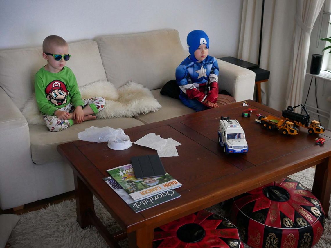 Elis, med solglasögon, och Folke, med Captain America-dräkt, i soffan framför tv:n