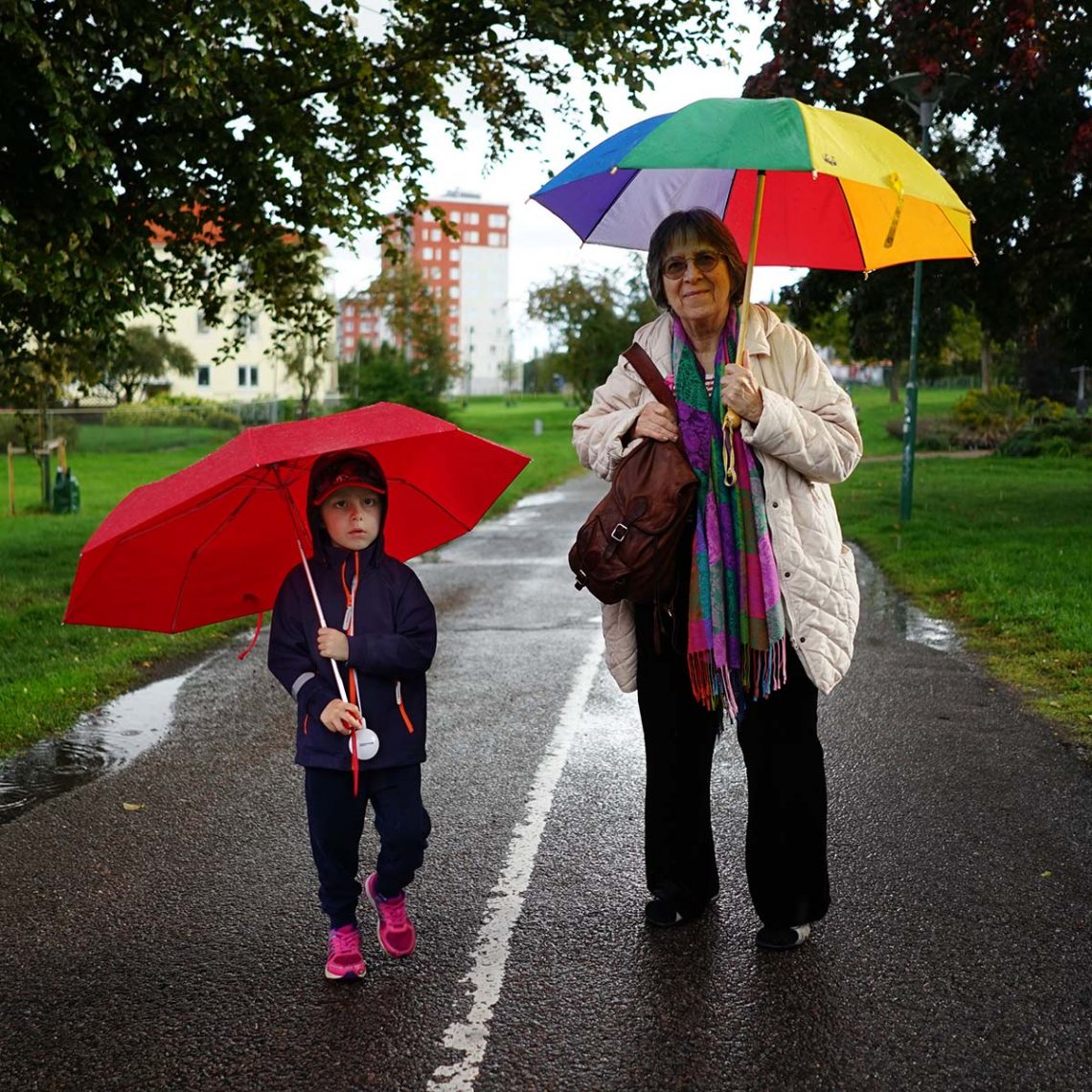 Elis och farmor under färgglada paraplyer, på väg till lekplatsen