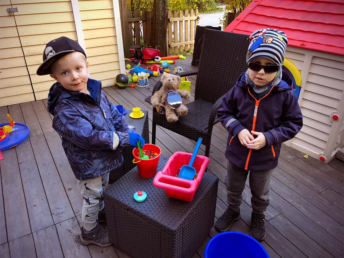 Folke och Elis på uteplatsen med nypon och vatten i en hink