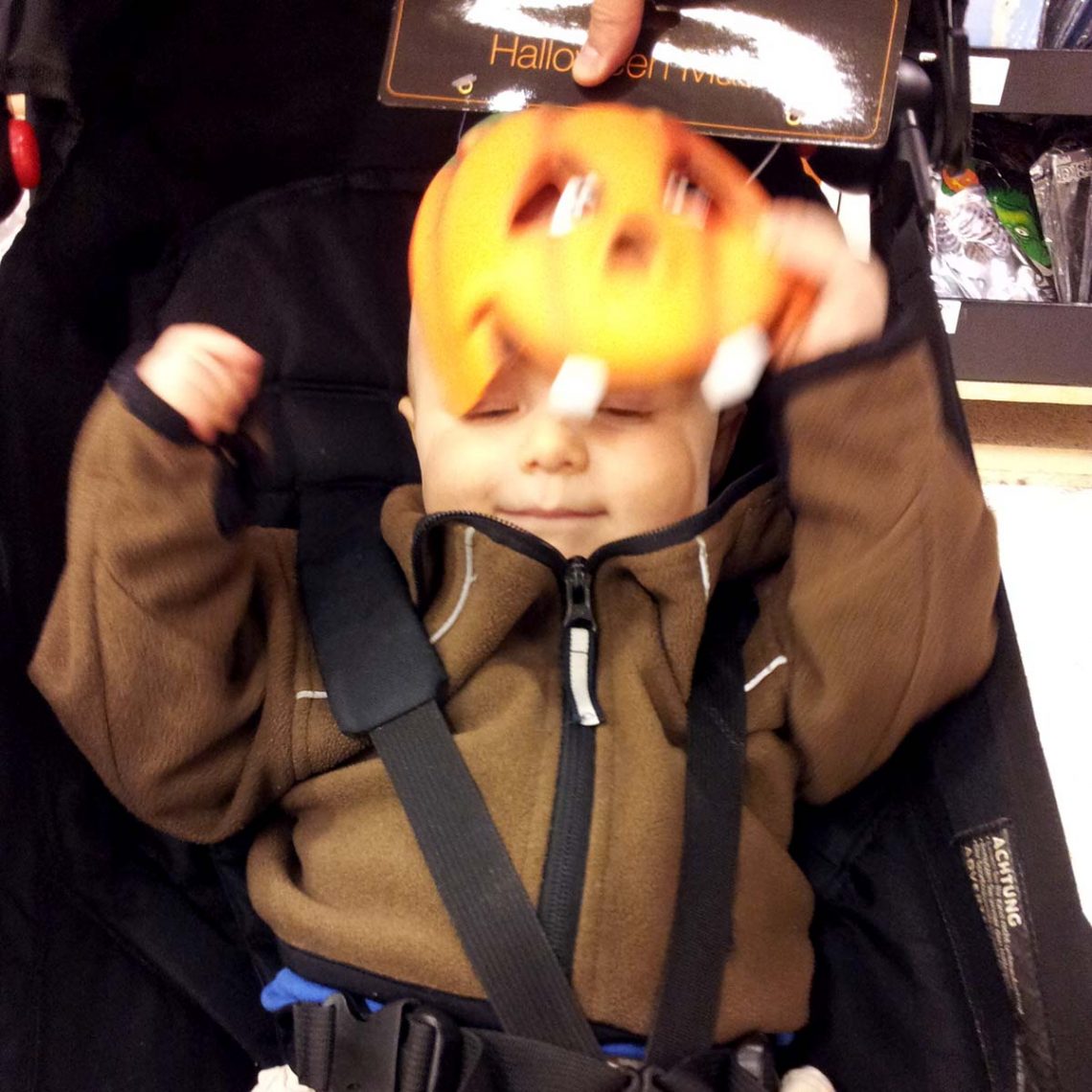 Elis, ett år gammal, puttar bort en pumpamask från ansiktet