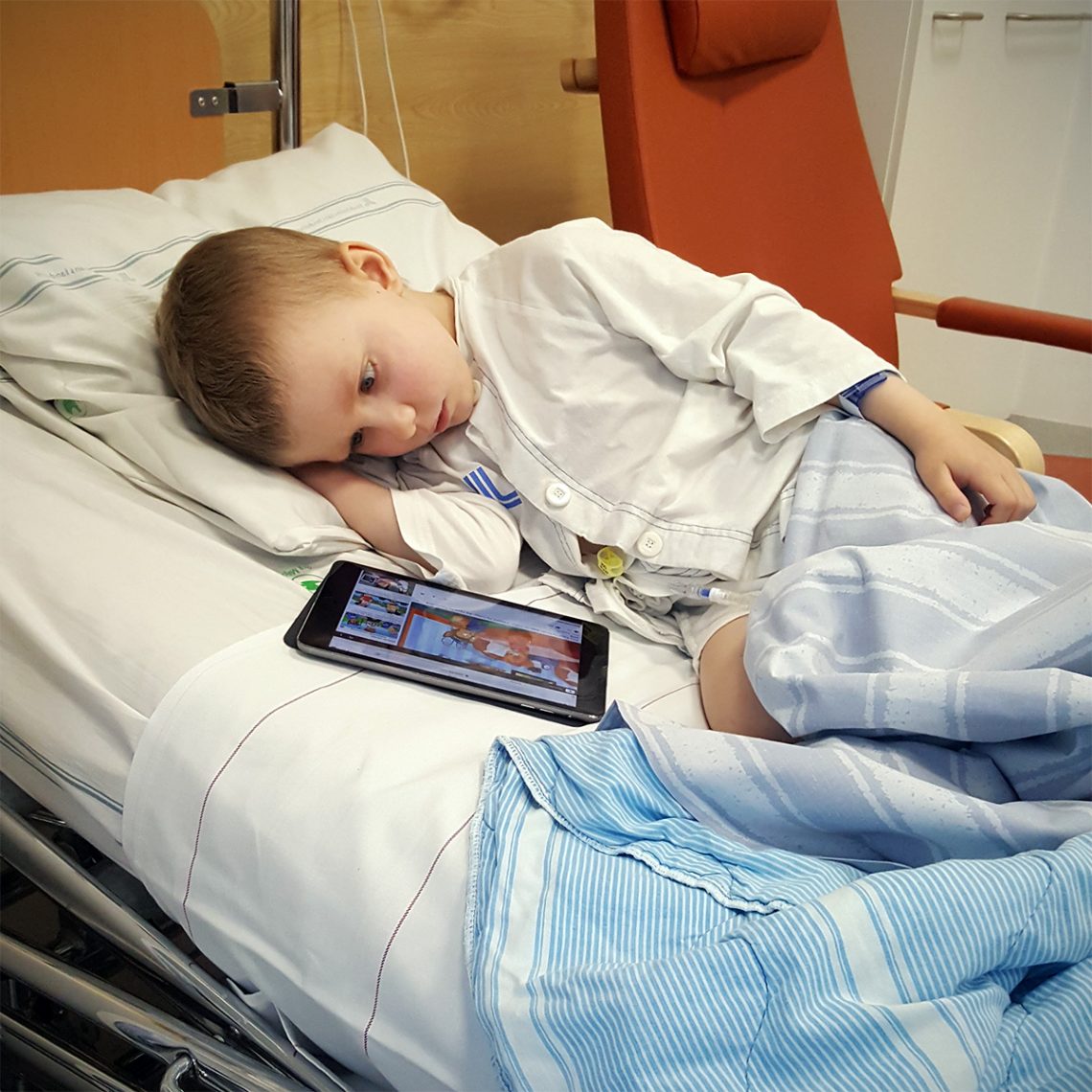 Elis ligger i sängen med iPaden, strax innan han ska iväg och operera tumören i ryggen