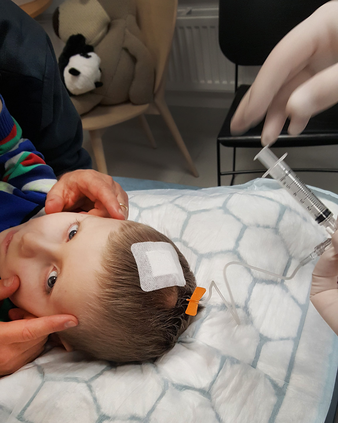 Elis får cytostatika i sin omaya-dosa i huvudet, medan pappa distraherar och lugnar