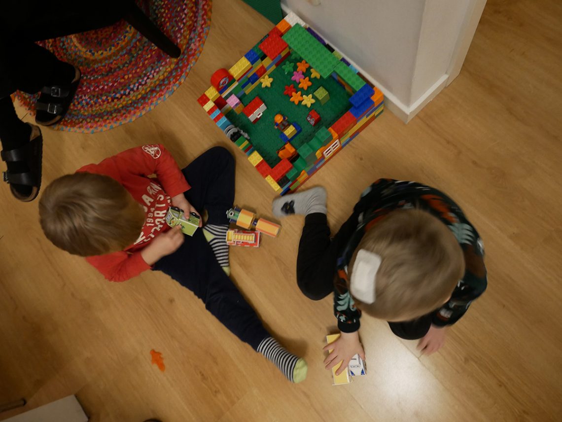Folke och Elis sitter på golvet hemma och leker med Duplo