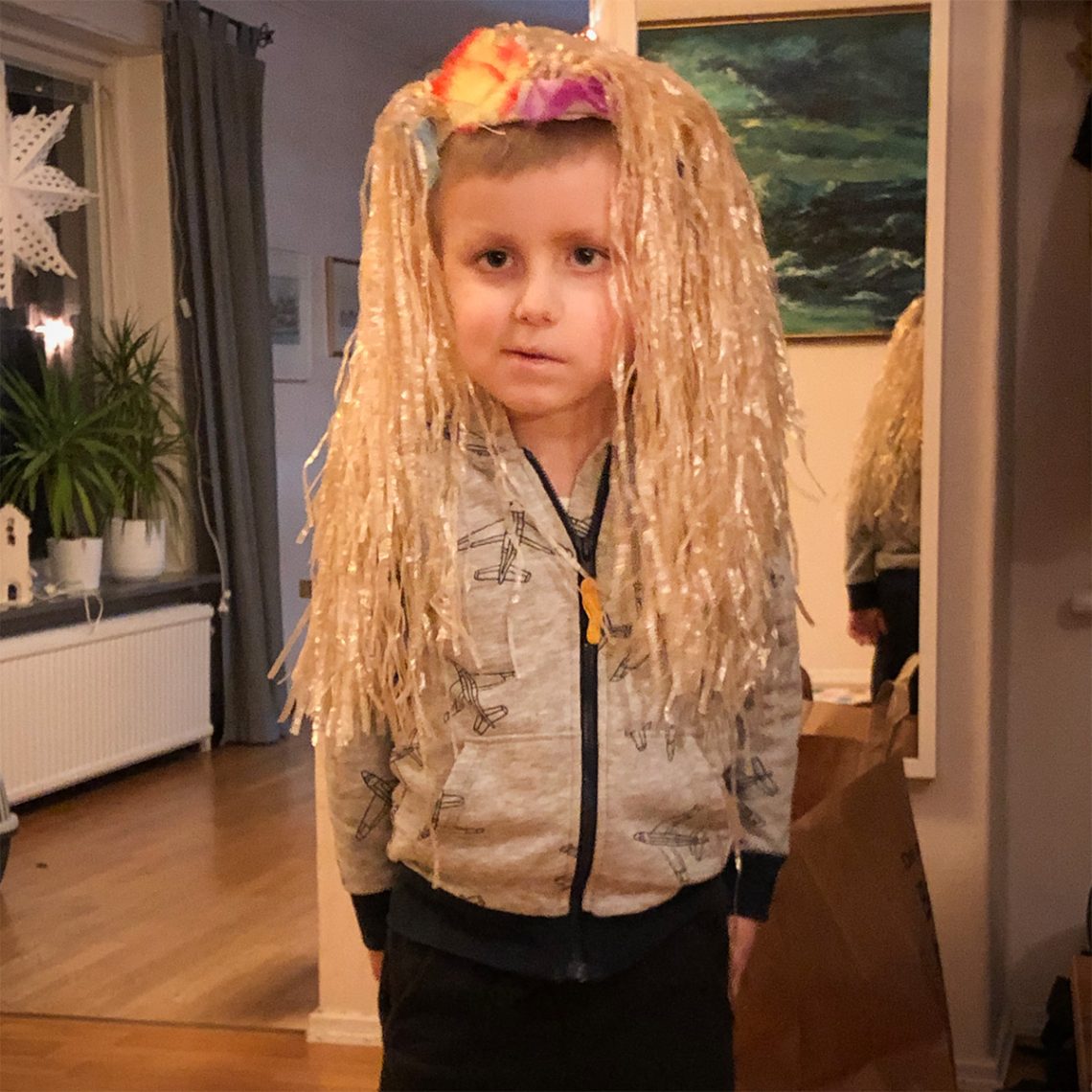 Elis provar en peruk med långt ljust hår