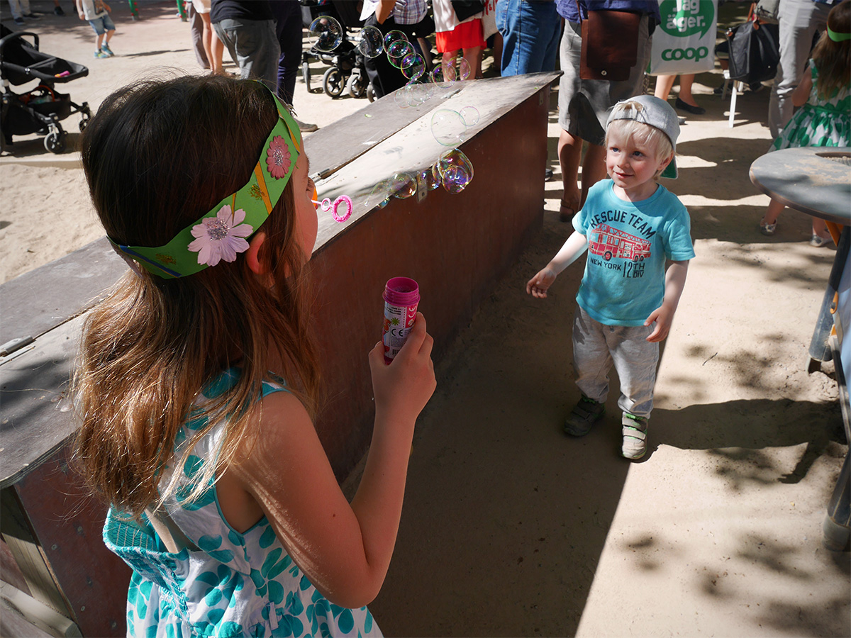 Ett större barn hänför Elis med såpbubblor, juni 2015