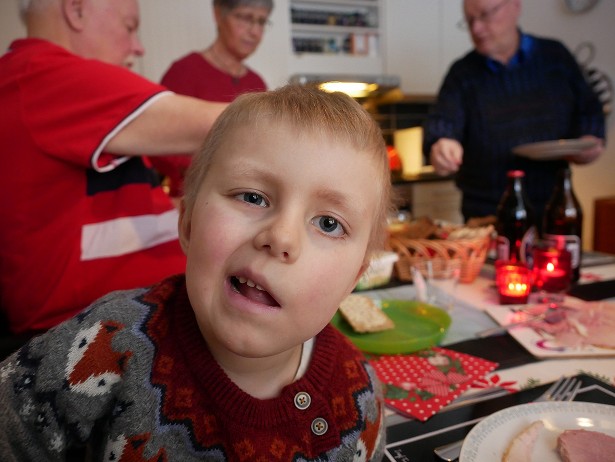Elis vid matbordet med morfar, mormor och farfar i bakgrunden