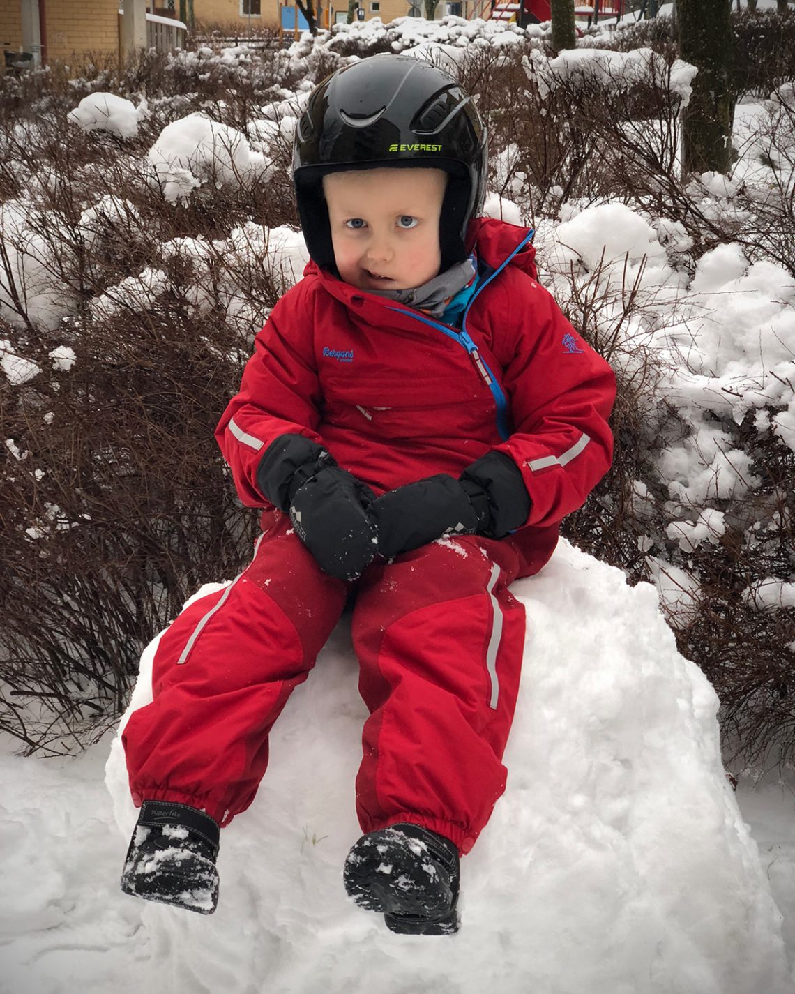 Elis sitter på ett snöklot och ler.