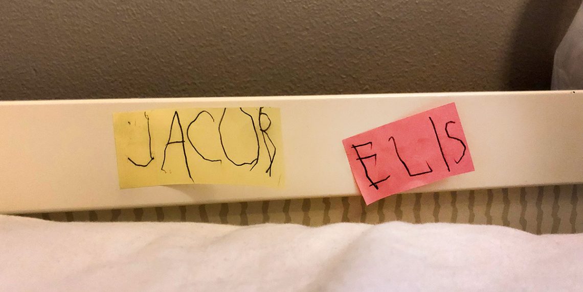 En gul post-it med texten JACOB och en rosa med texten ELIS, uppsatta på sänggaveln