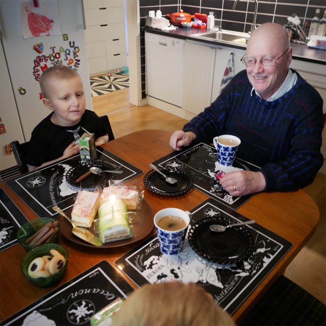 Elis och farfar skrattar runt bordet med födelsedagsfika