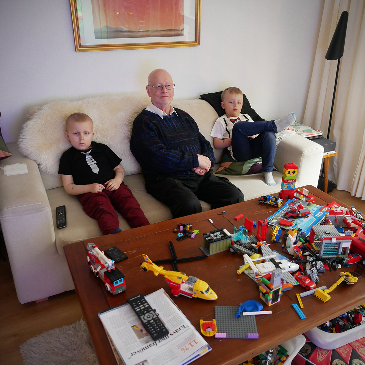 Elis, farfar och Folke i tv-soffan, med ett soffbord fullt av Lego.