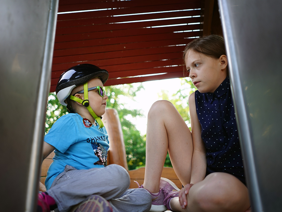 Elis och Lilly sitter uppe vid en rutschkana och pratar.