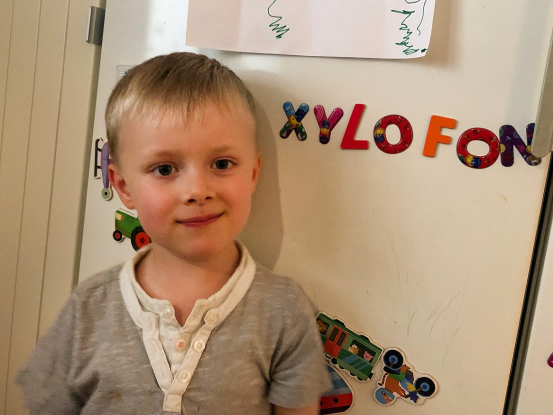 Folke framför kylskåpet där vi skrivit ordet "XYLOFON" med magnetiska bokstäver