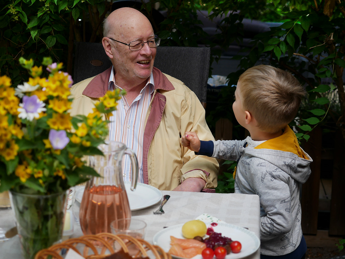 Farfar och Folke vid matbordet på uteplatsen