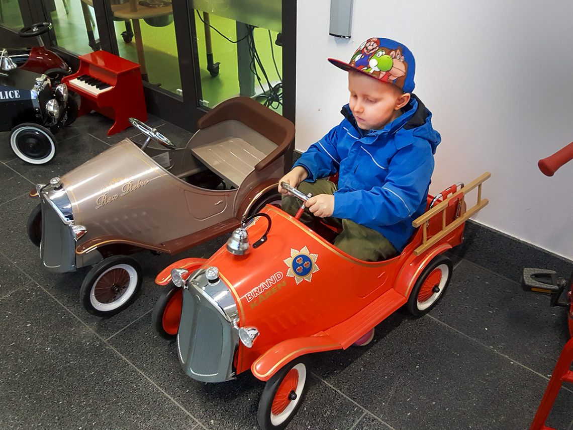 Elis sitter i en röd leksaksbrandbil utanför lekterapin