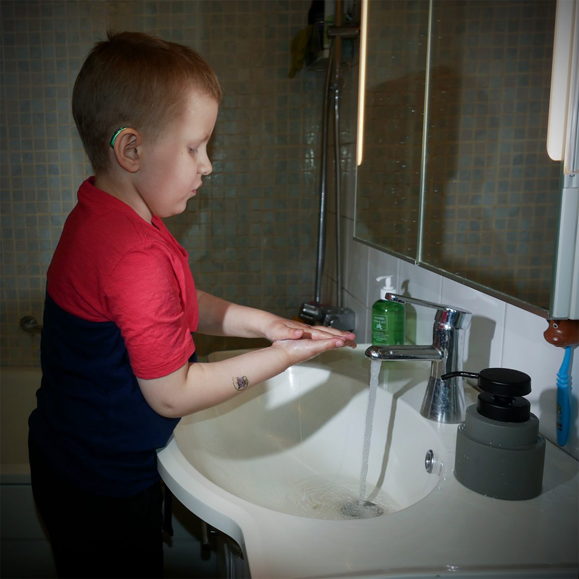 Elis tvättar händerna i badrummet