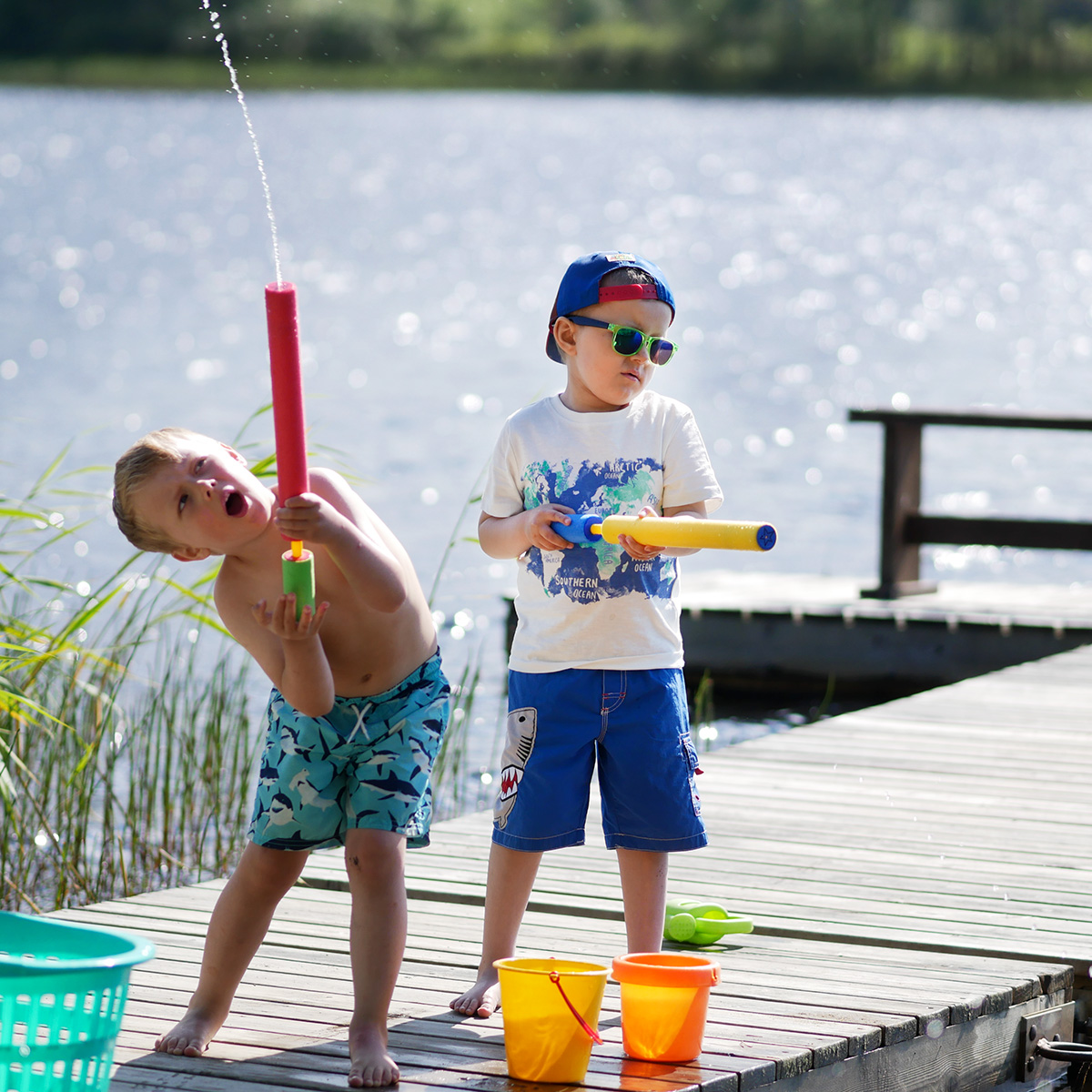 Folke och Elis med vattensprutor på bryggan