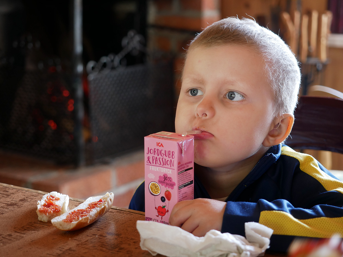Elis dricker fruktdryck tillsammans med ett par korvbröd med ketchup