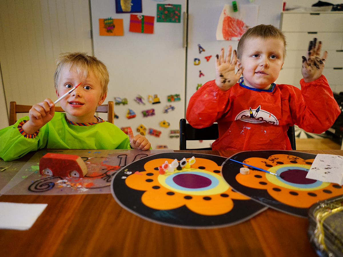 Folke och Elis visar målarpenslar och kladdiga händer.