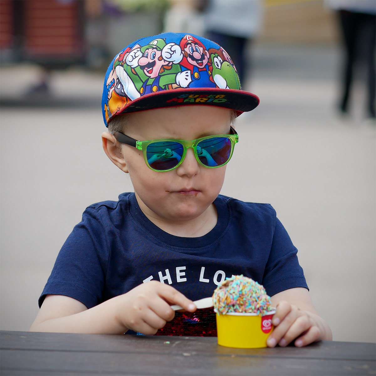 Elis äter chokladglass med strössel ur en gul pappbägare