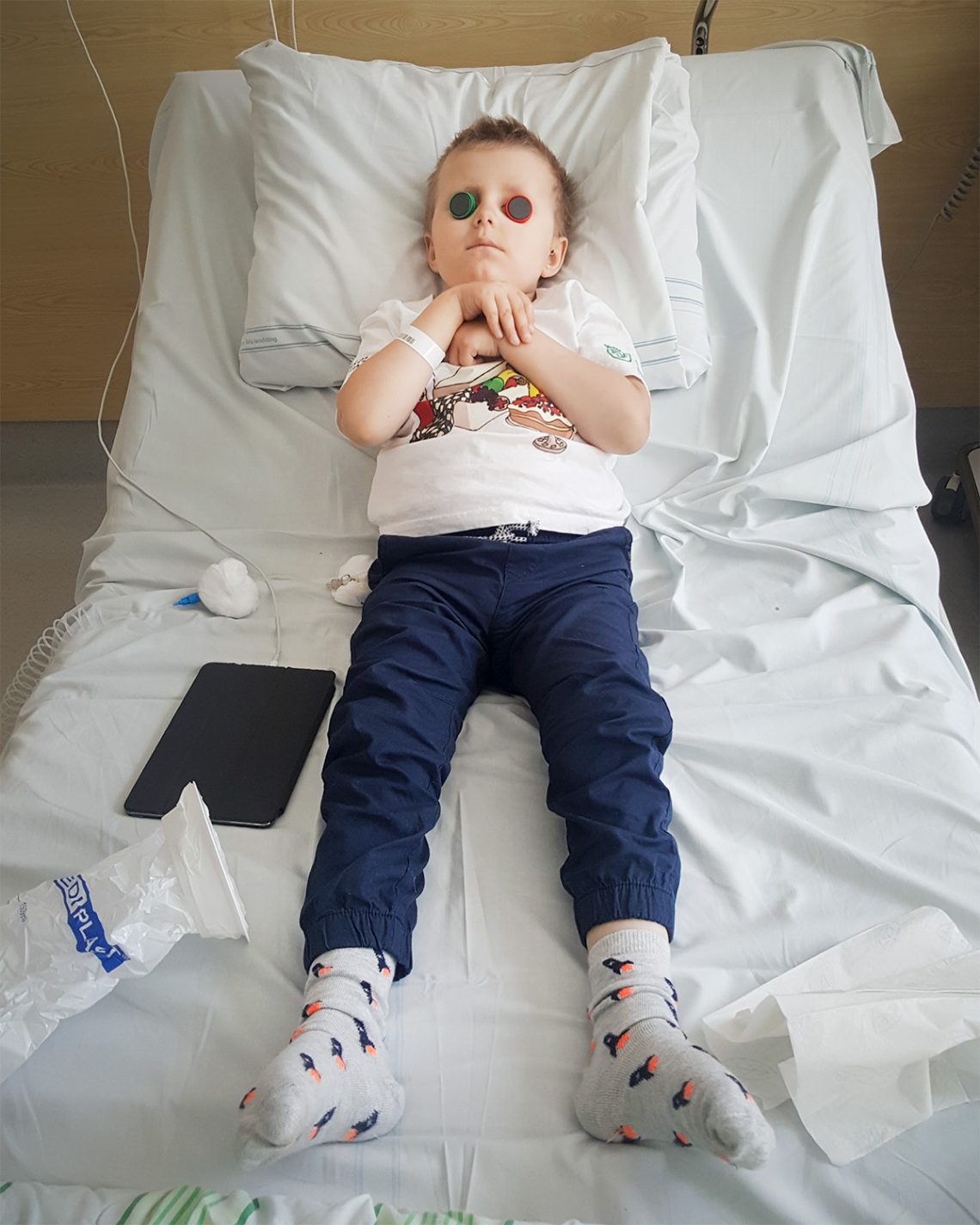 Elis ligger i sängen på sjukhuset, och har lagt magneter över sina ögon på skoj.