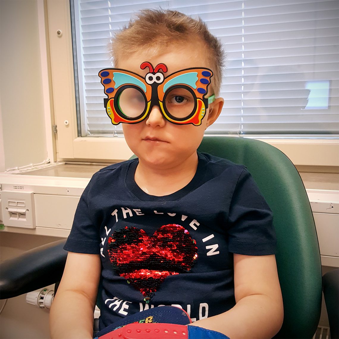 Elis hos ögonläkaren, med ett par glasögon som ser ut som en fjäril.