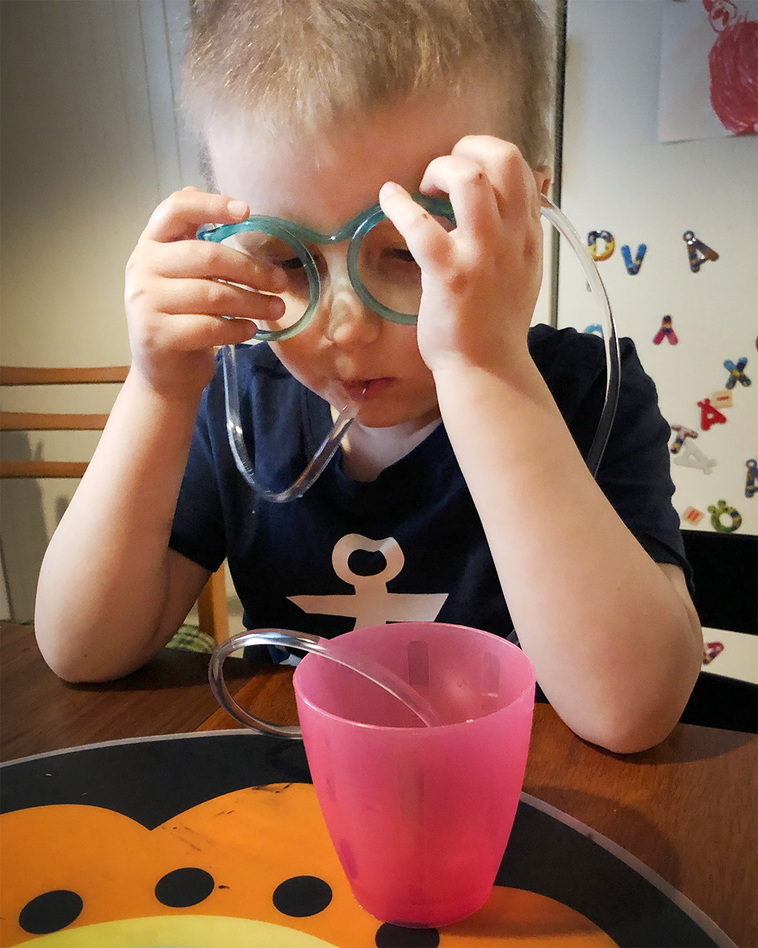 Elis dricker ur ett glas med ett långt roligt sugrör som är format till ett par glasögon