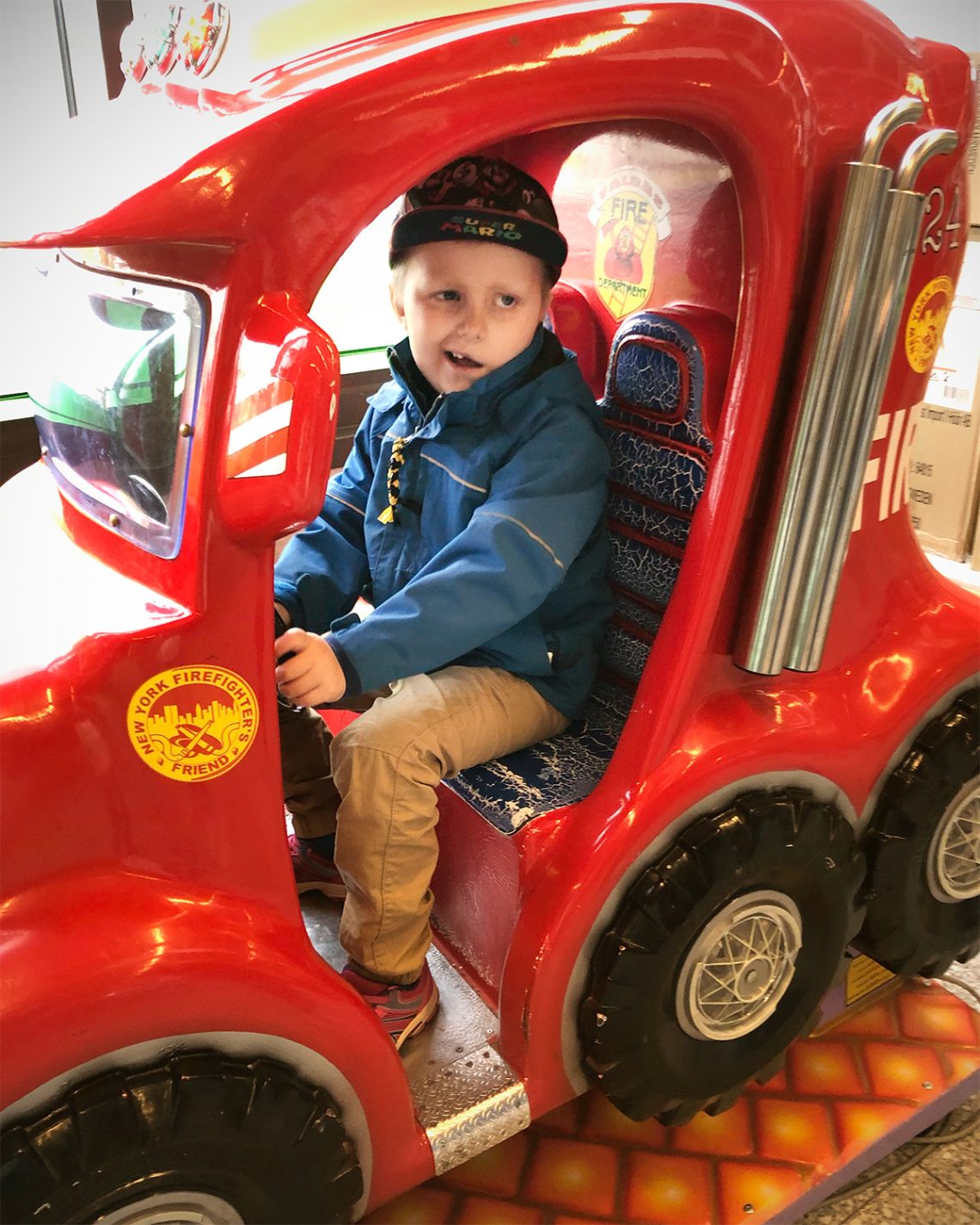 Elis sitter i en brandbil i entren på Coop i Rissne och ler