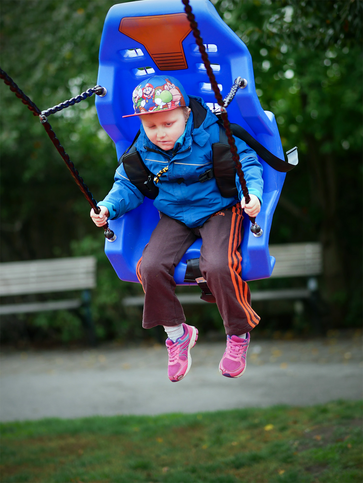 Elis testar en annorlunda gunga, en blå plaststol med säkerhetsbälten