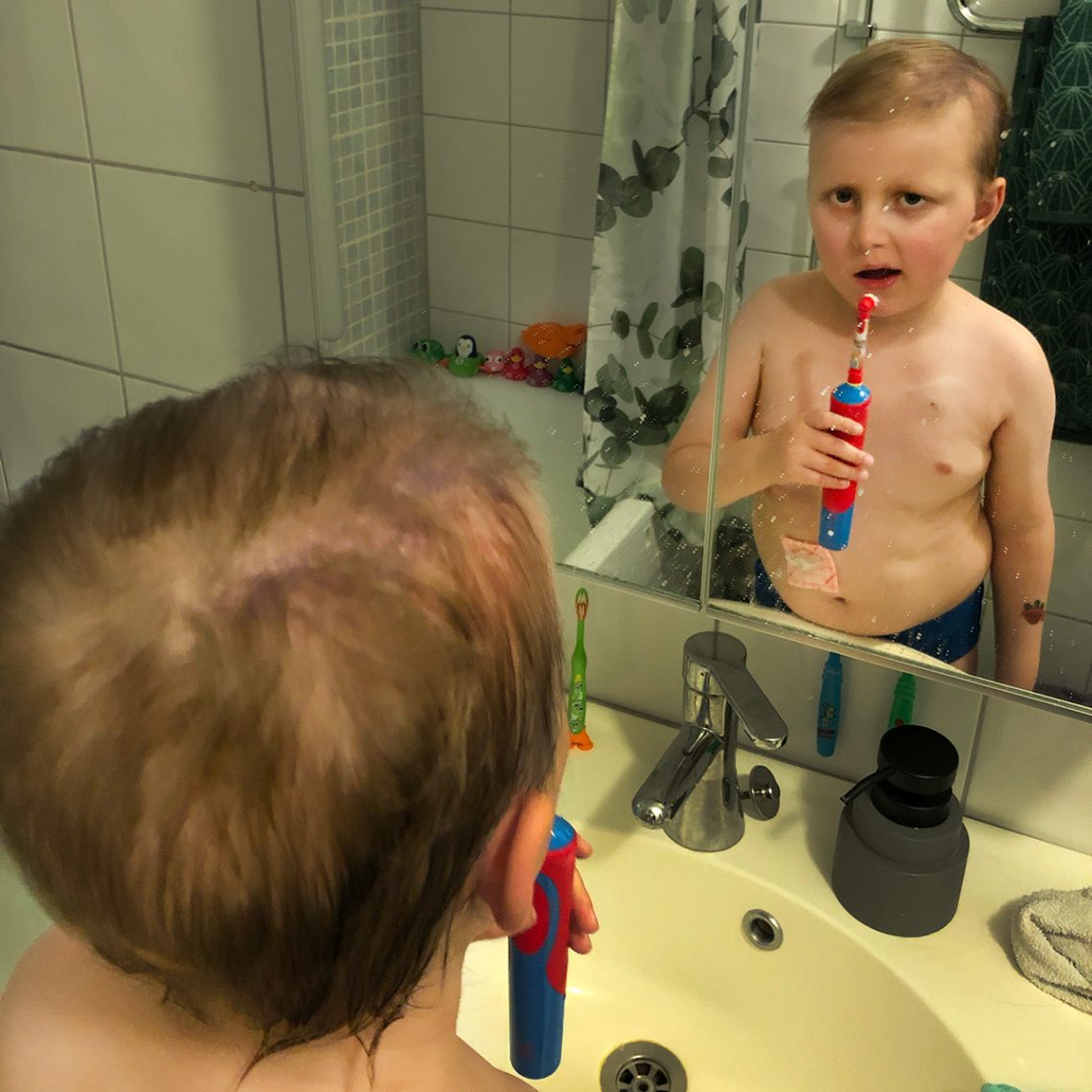 Elis i badrumsspegeln med tandborsten i handen