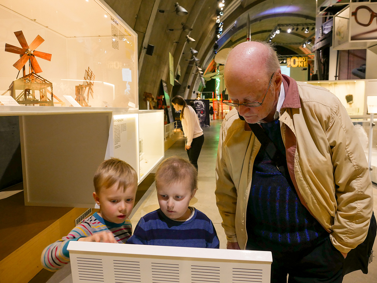 Folke, Elis och farfar tittar på en skärm på Tekniska museet