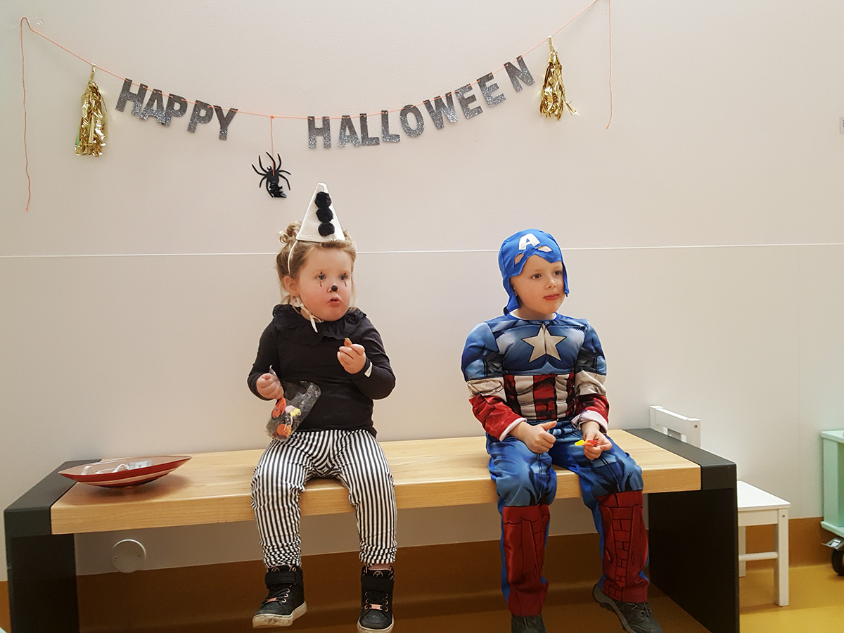 Saga och Folke äter godis framför en Happy Halloween-skylt