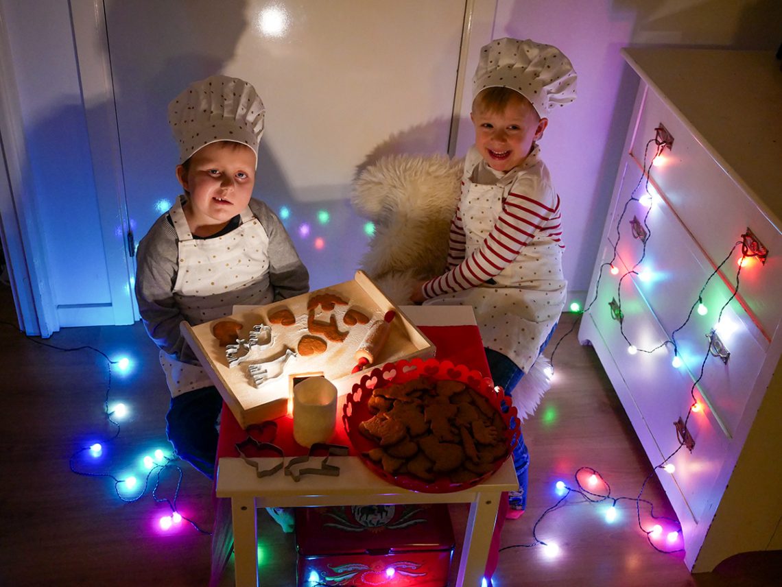 Elis och Folke poserar för årets julkort, vid ett litet bord med pepparkakor