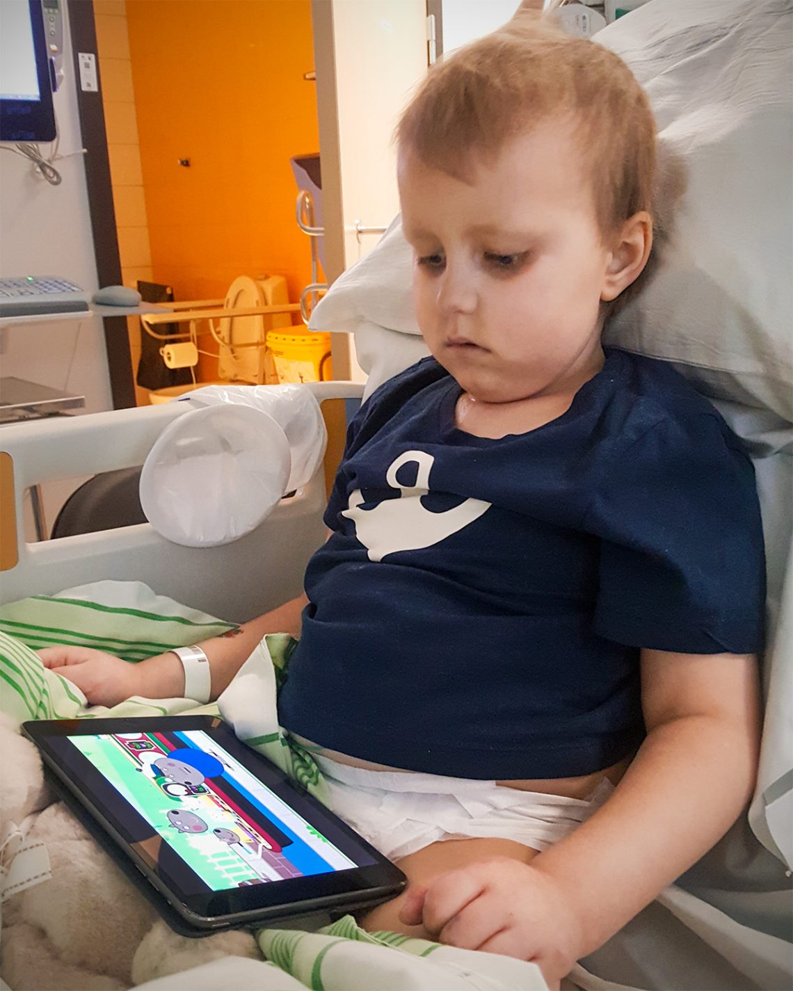 Elis sitter i sängen på intensiven och tittar på Greta Gris