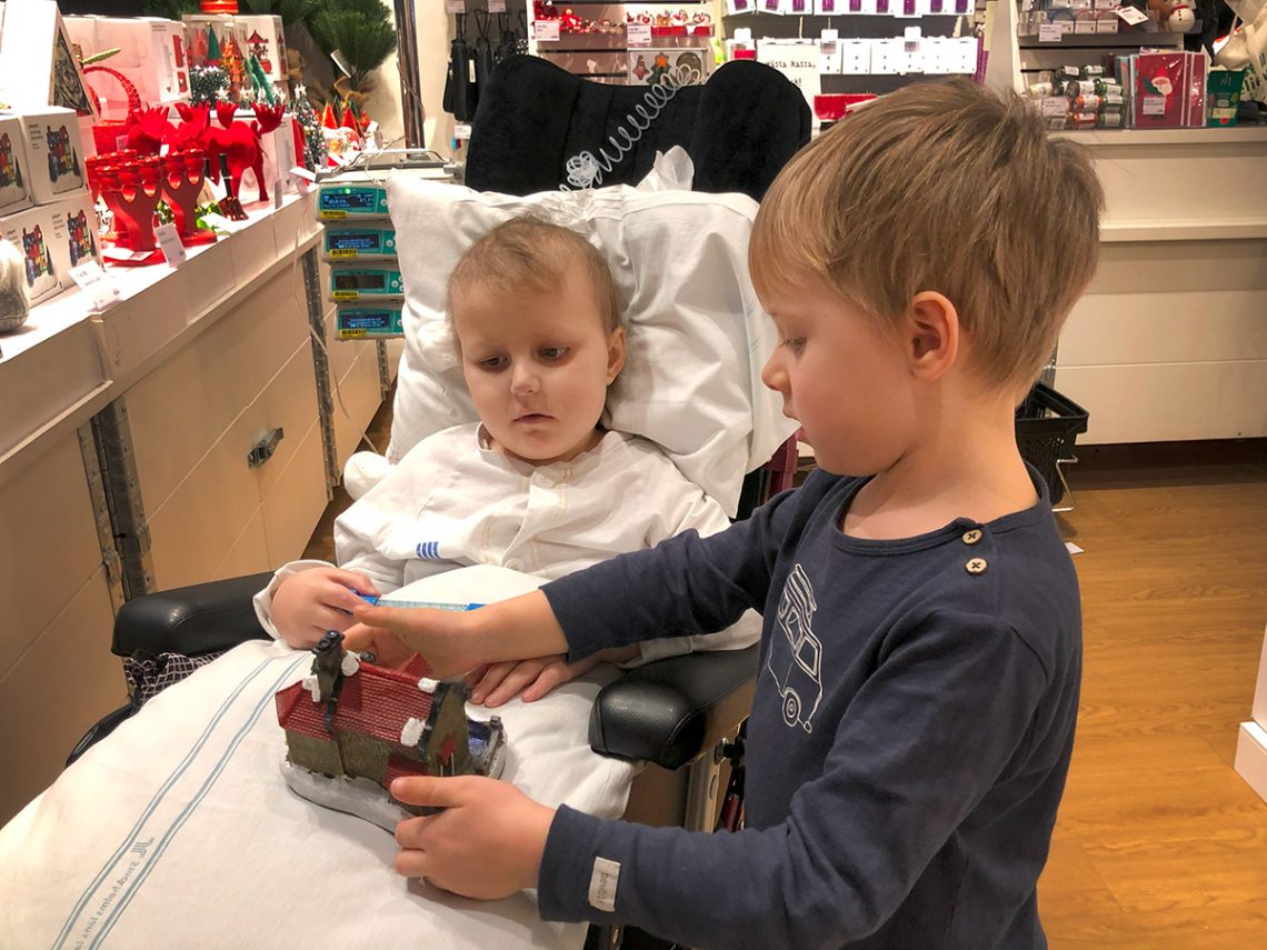 Elis sitter i sin nya komfortrullstol och tittar på julsaker inne på TGR, tillsammans med Folke.