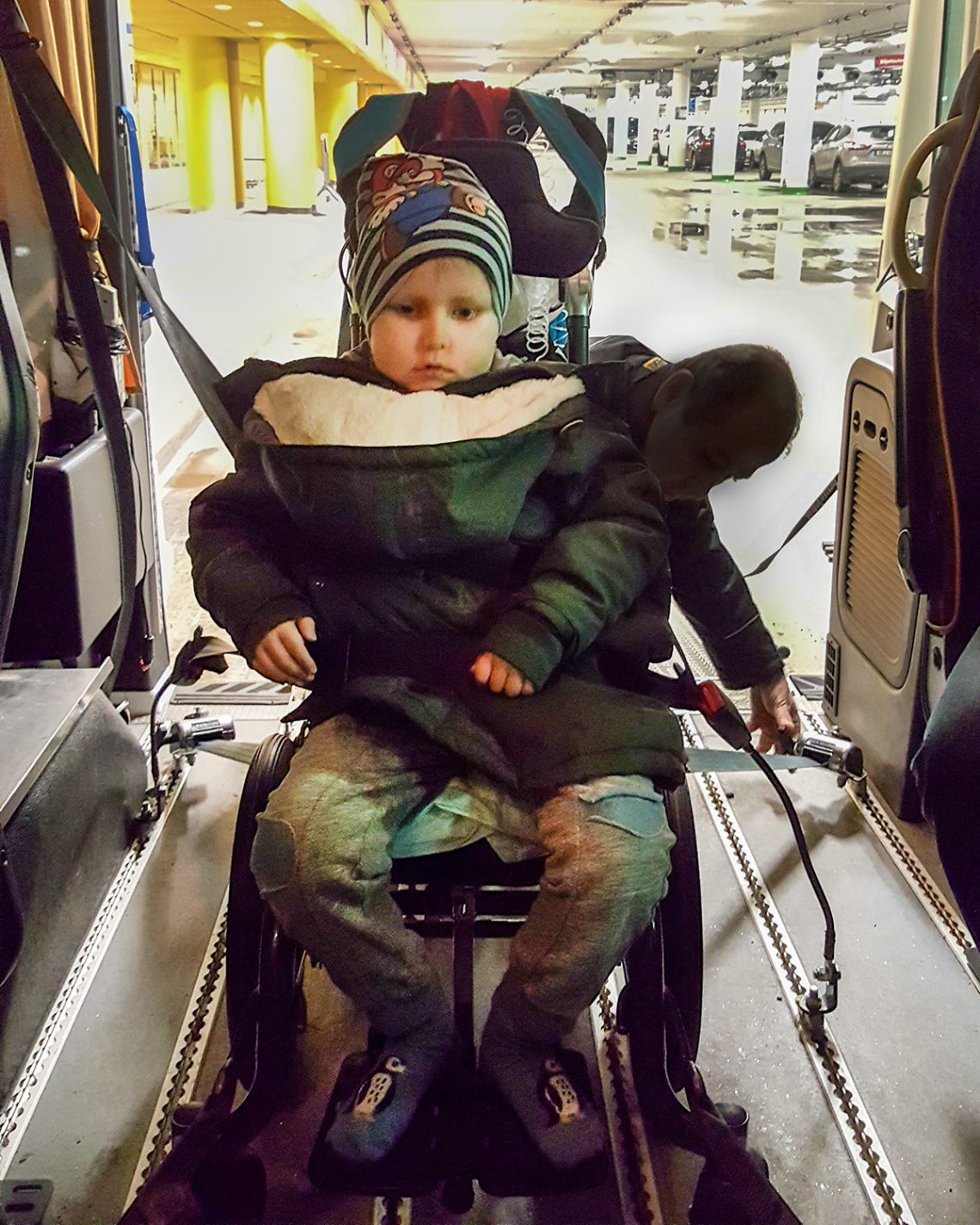 Elis i rullstolstaxin, medan föraren spänner fast hans stol i golvet.