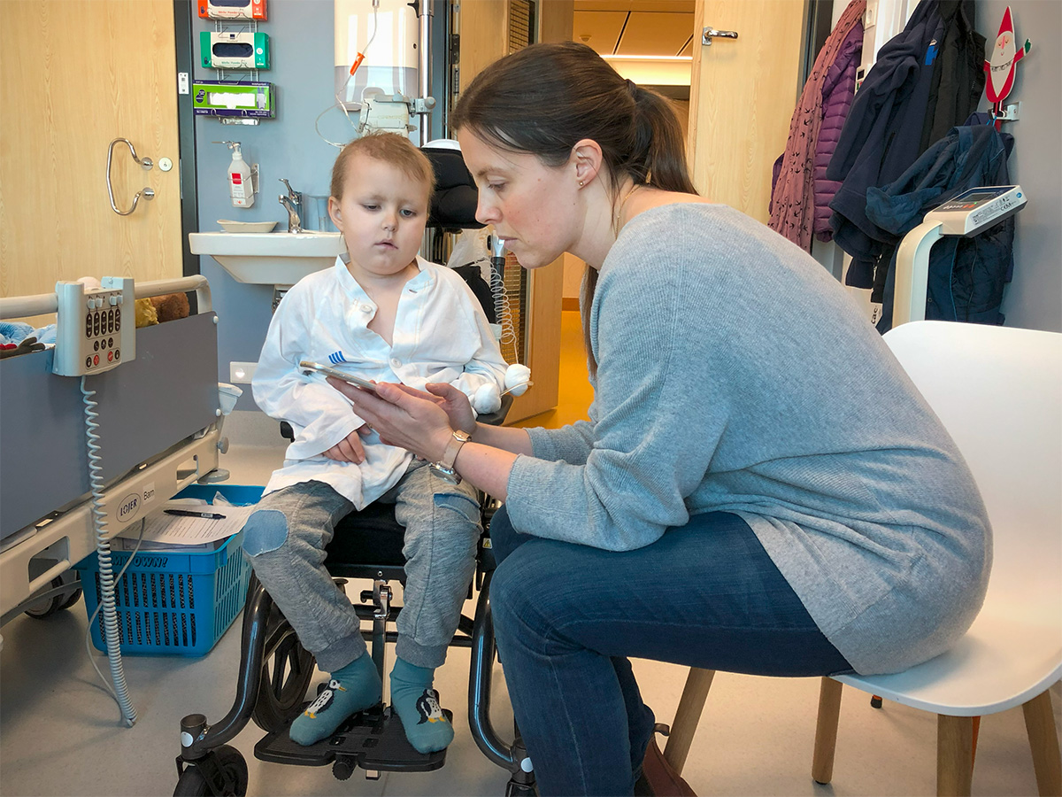Mamma visar något på mobilen för Elis inne på vårt rum på sjukhuset