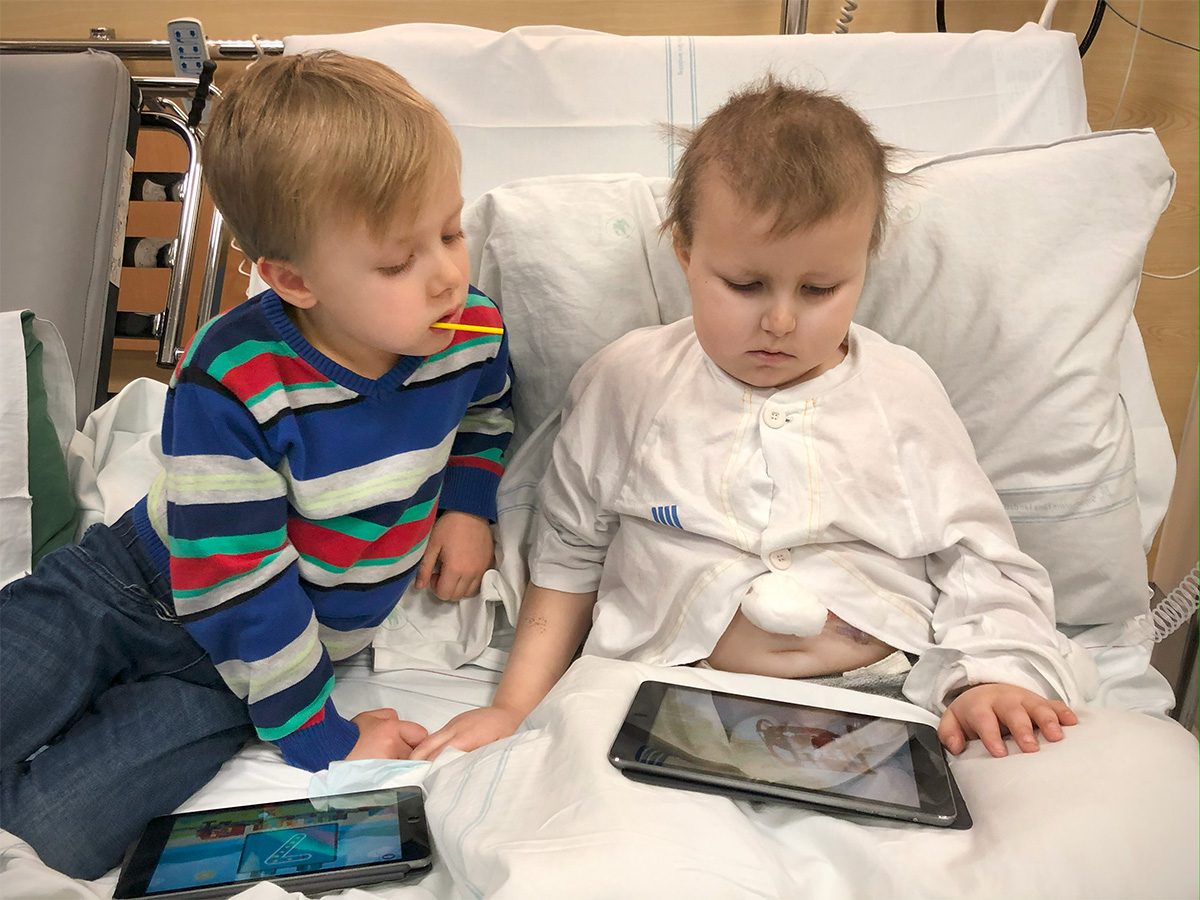 Folke och Elis i sjukhussängen med iPads