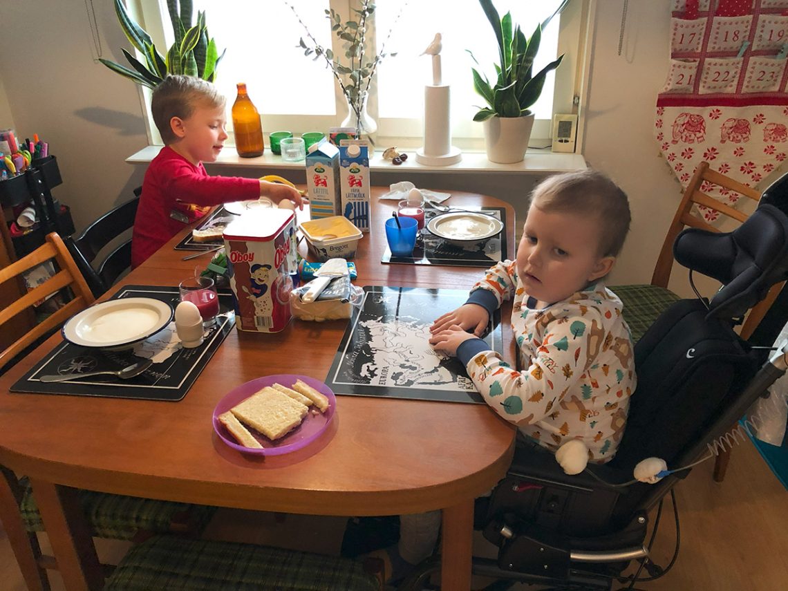 Folke och Elis vid frukostbordet - Elis sitter i sin nya komfortrullstol
