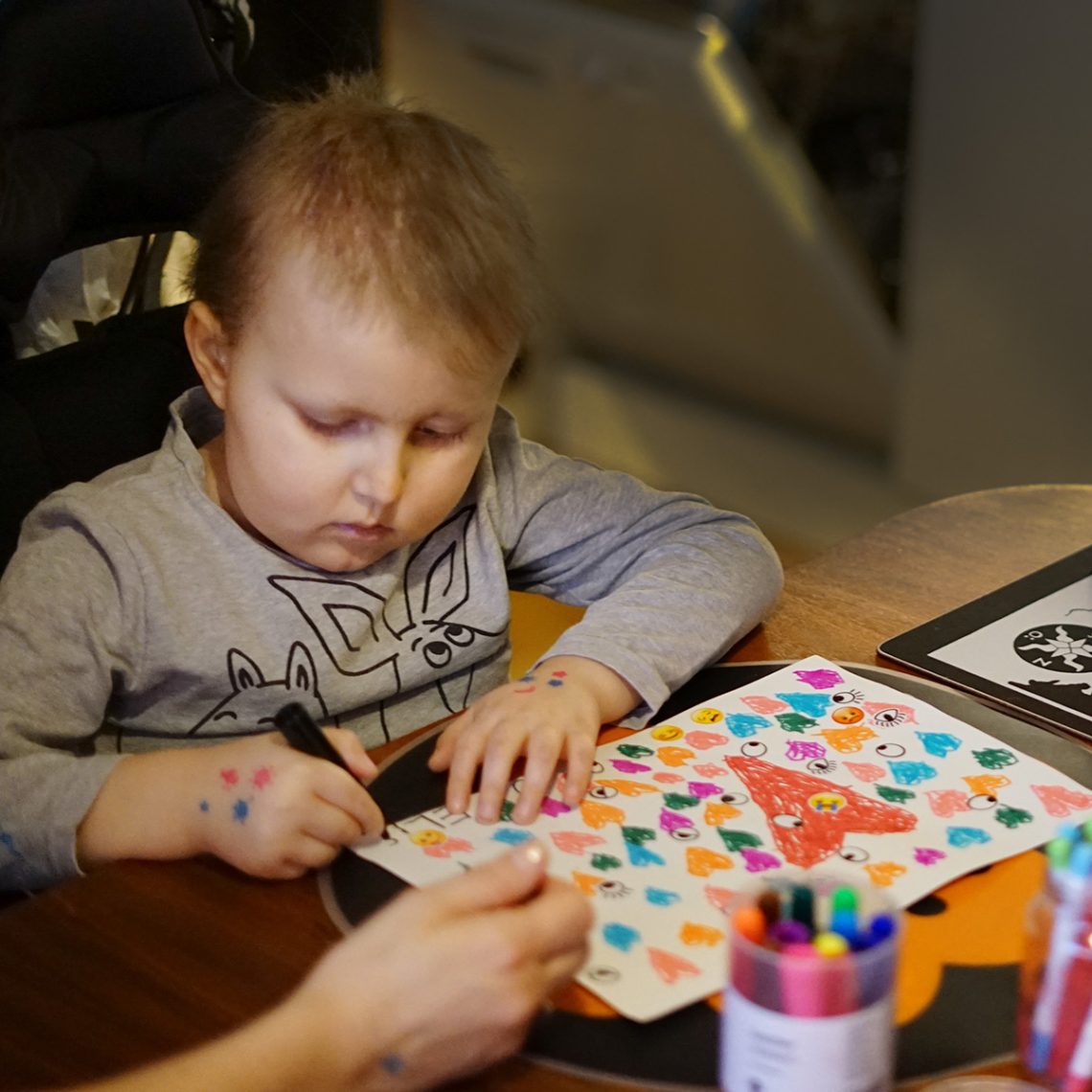 Elis sitter och ritar en teckning full av färgglada hjärtan.